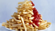 Ein Berg Pommes Frites mit Ketchup auf einem Teller.