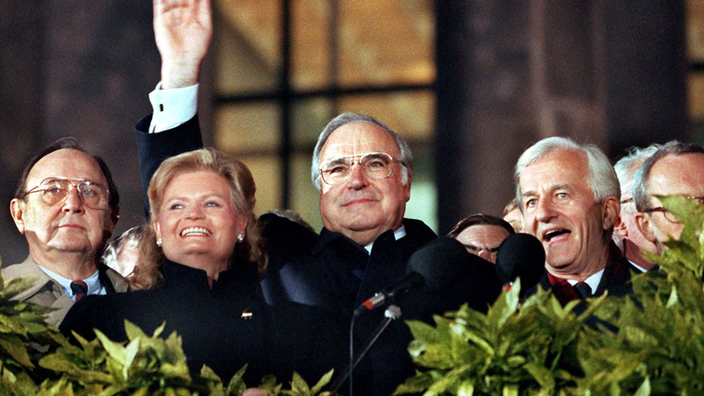 Helmut Kohl winkt von einem Balkon, neben ihm seine Frau Hannelore, Außenminister Hans-Dietrich Genscher sowie Bundespräsident Richard von Weizsäcker.