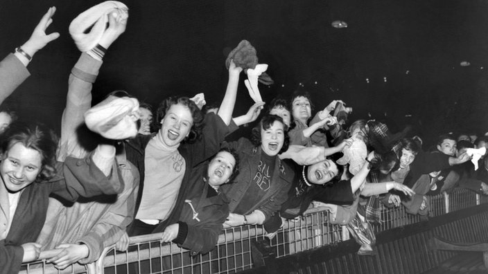 Auf der Schwarzweiß-Fotografie sieht man jubelnde, jugendliche Fans.