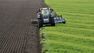 Ein Traktor beim Pflügen eines Ackers.