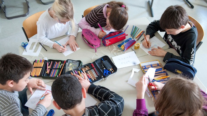 Sechs Kinder malen an einem Tisch