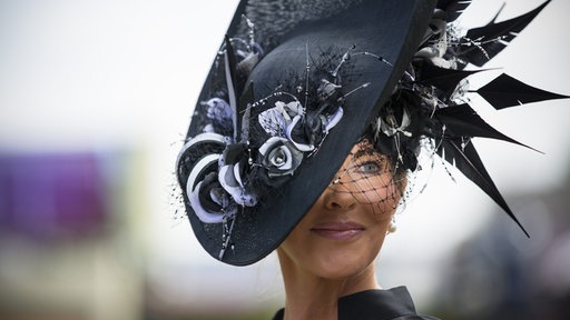 Eine Dame mit schwarzer Hutkreation beim Pferderennen in Ascot