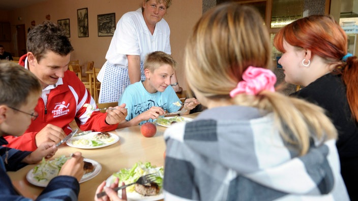 Mehrere Jugendliche sitzen gemeinsam am Tisch, essen und unterhalten sich.