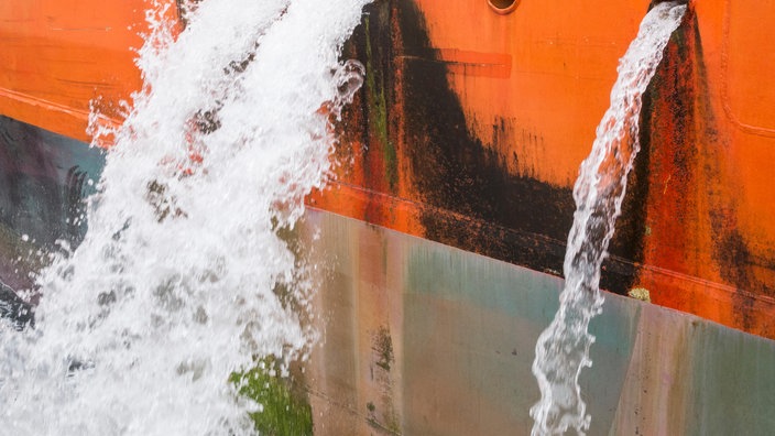 Ein Schiff lässt Wasser aus mehreren Luken ab.