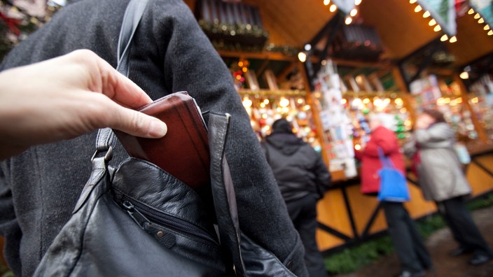 Jemand klaut eine Geldbörse aus einer Handtasche