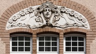 Verschnörkelte Figur oberhalb eines Fenster an einem Haus aus der Gründerzeit.