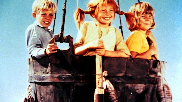 Filmszene aus Pippi Lamgstrumpf. Pippi, Annika und Tommi sitzen in einem Ballonkorb.