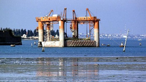 Bauarbeiten in der Lagune von Venedig. Mehrere Kräne stehen im Wasser.