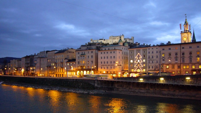 Salzburger Altstadt mit herausragenden Kirchentürmen in der Abenddämmerung. Auf einer Anhöhe die große Burganlage.