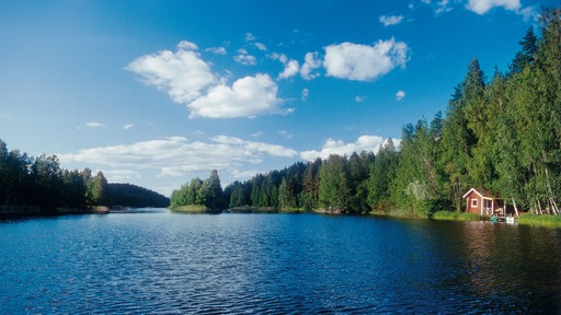 Blick auf den Saimaa-See mit einer roten Hütte am Ufer