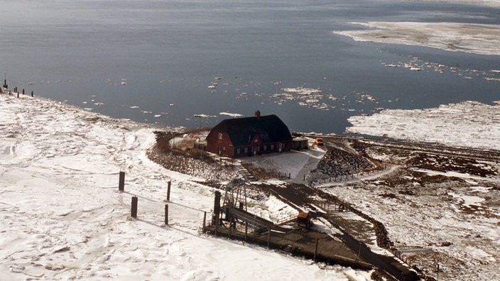 Luftbild von der Hallig Langeneß. Einsames Haus im vereisten Wattenmeer.