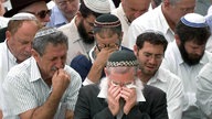 Mehrere weinende Männer mit Kippa auf dem Kopf.