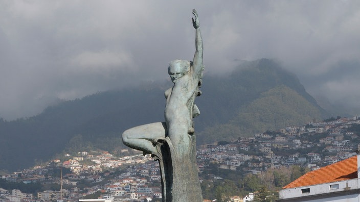 Das Denkmal für die Nelkenrevolution auf Madeira stellt einen Menschen dar, der sich aus einer Steinsäule in den Himmel streckt.