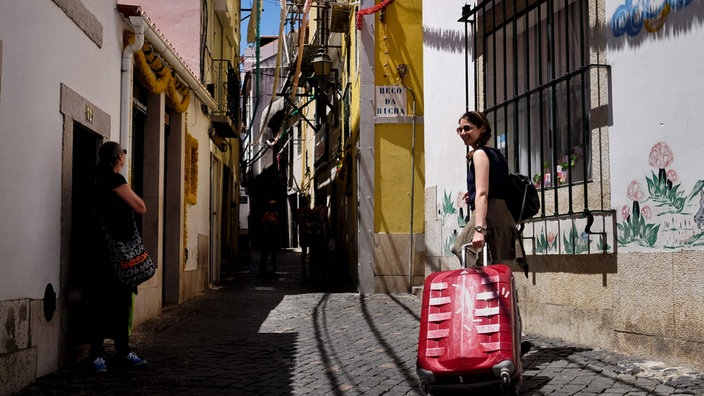 Frau mit Koffer in einer Gasse in Lissabon