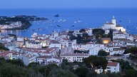 Blick von oben auf die weißen Häuser von Cadaques vor abendlichem Himmel