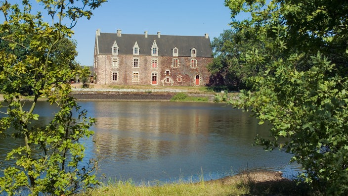 Blick über einen kleinen See auf ein Schloss.