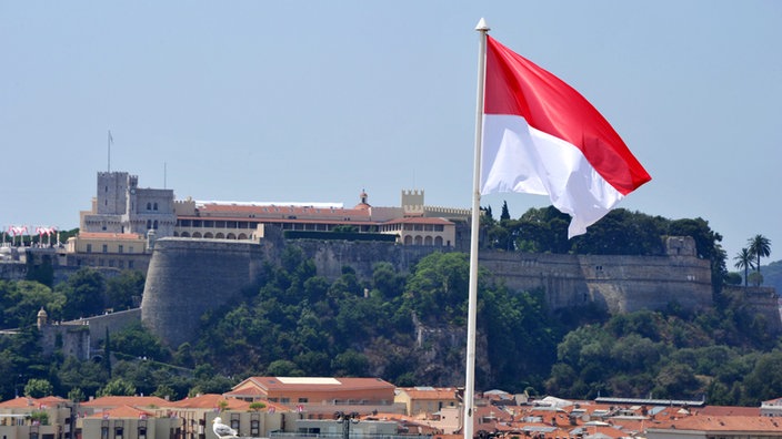 Die monegassische Flagge. Im Hintergrund der Palast der Grimaldis.