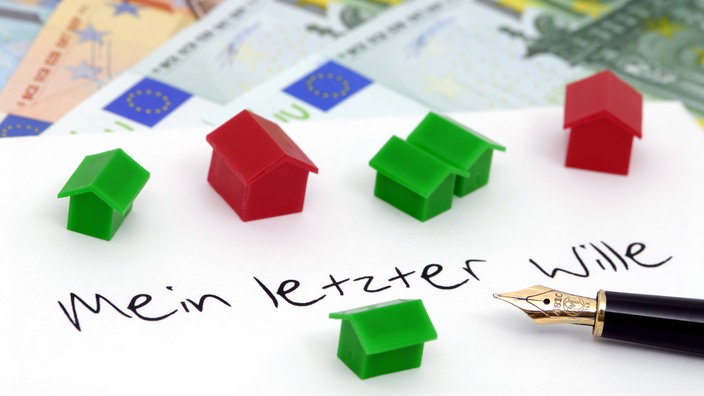 Füller und Blatt Papier mit der Aufschrift "Mein letzter Wille". Darauf liegen Monopoly-Häuser, darunter Geld.