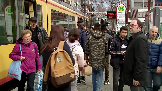 Menschen an einer Straßenbahnhaltestelle.