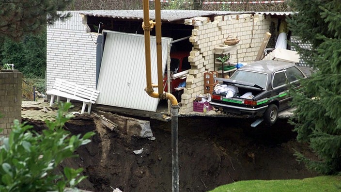 Bergschaden in einem Wohngebiet in Bochum-Wattenscheid am 2. Januar 2000: Vor einem Haus tut sich ein großes Loch auf. Teile des Fundaments und eines Autos, das vor dem Haus geparkt ist, hängen über den Grubenrand.